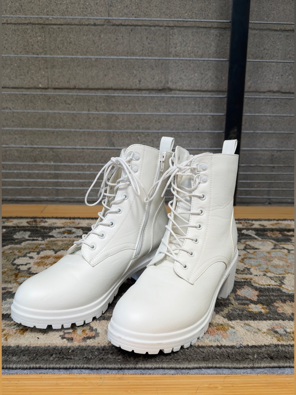 Pair of white lace-up combat boots with chunky lug soles and side zippers